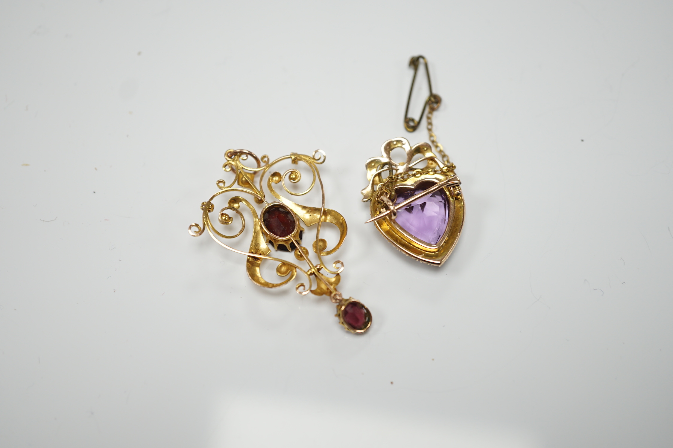 An early 20th century yellow metal, amethyst and seed pearl cluster set heart shaped brooch, 27mm, together with a similar yellow metal and two stone garnet set drop pendant, gross weight 9.3 grams.